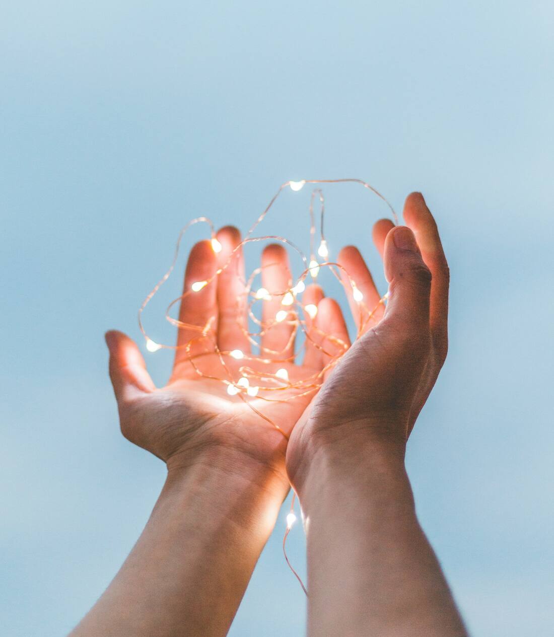 Deux mains ouvertes recueillant une lumière douce et chaleureuse — évocation du magnétisme